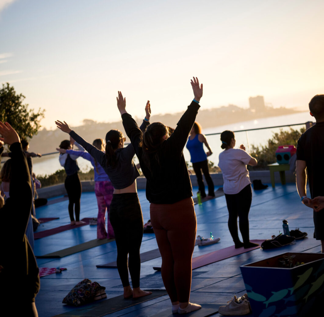 Group of people doing outdoor yoga on the waterfront