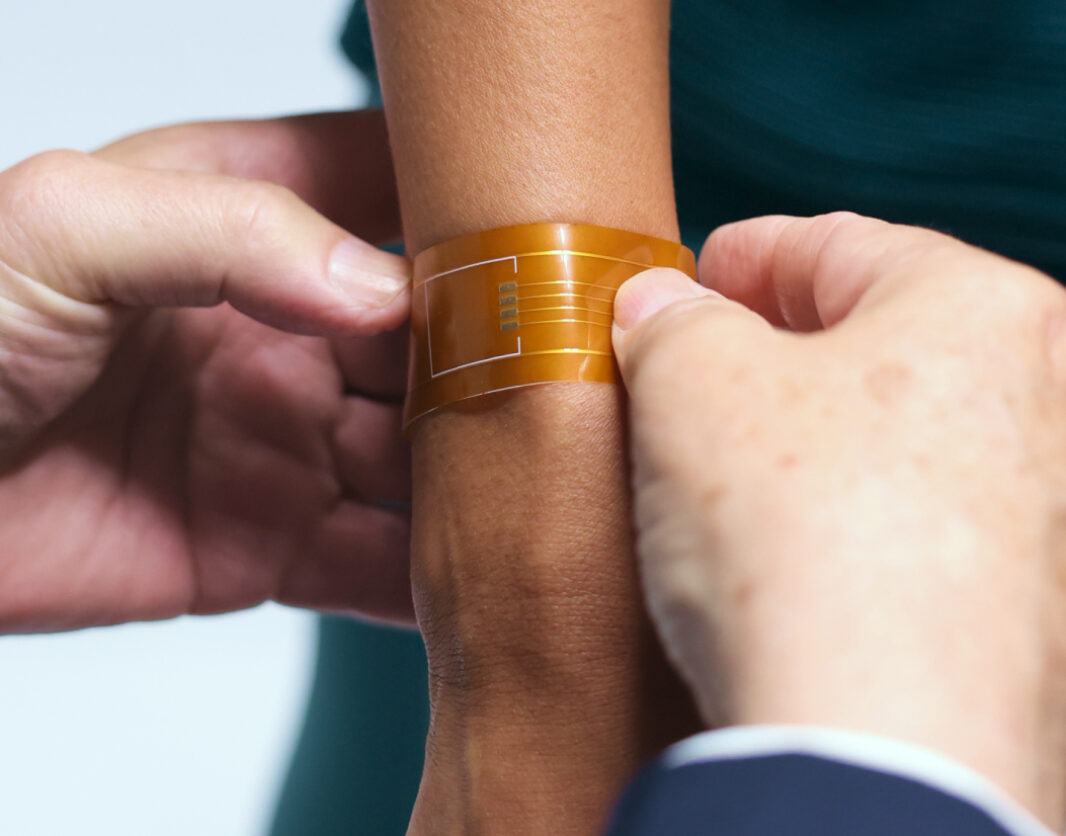 A man places a wearable technology bracelet on a patient's wrist
