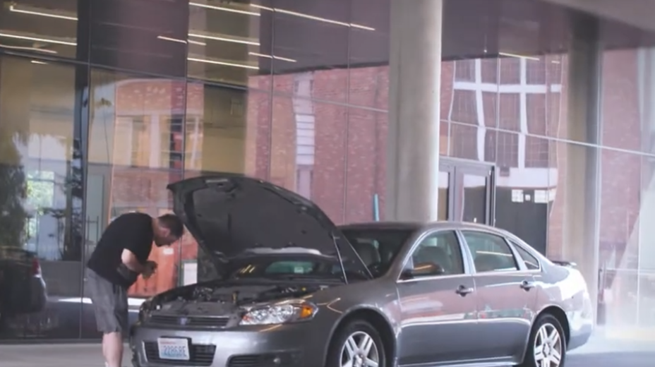 A man inspects the hood of a car.